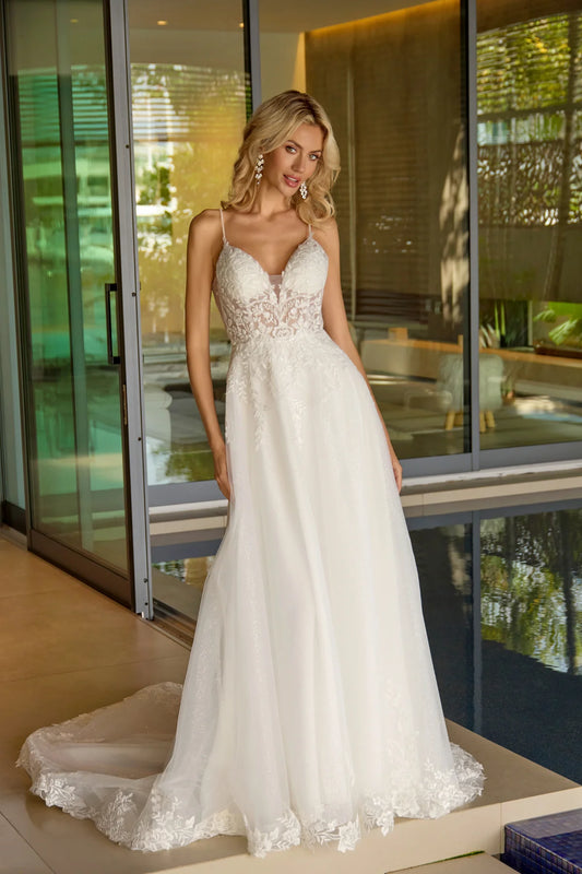 Woman in a white wedding dress standing in front of a glass door.
