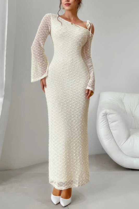 Woman wearing a long, elegant white dress with sheer sleeves in a minimalistic setting.