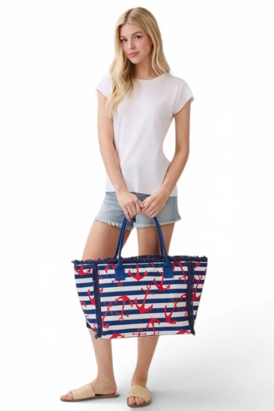 Woman holding a blue and red striped tote bag with anchor pattern on a white background