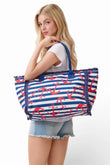 Woman holding a large tote bag with blue and white stripes and red anchor patterns.
