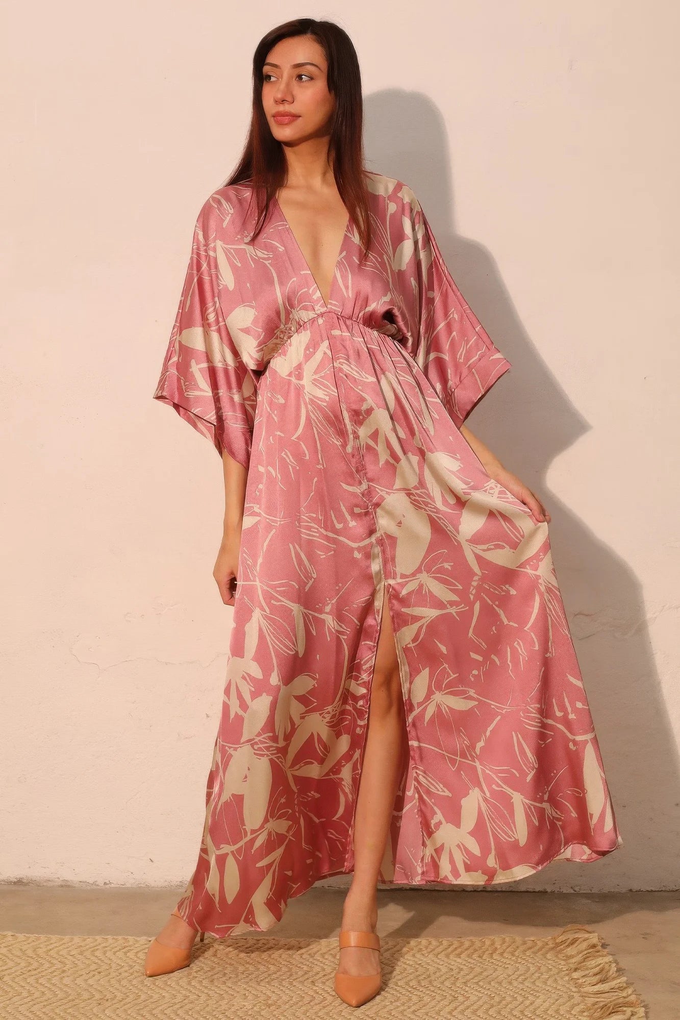 Woman wearing a pink and white floral kimono-style dress against a plain background