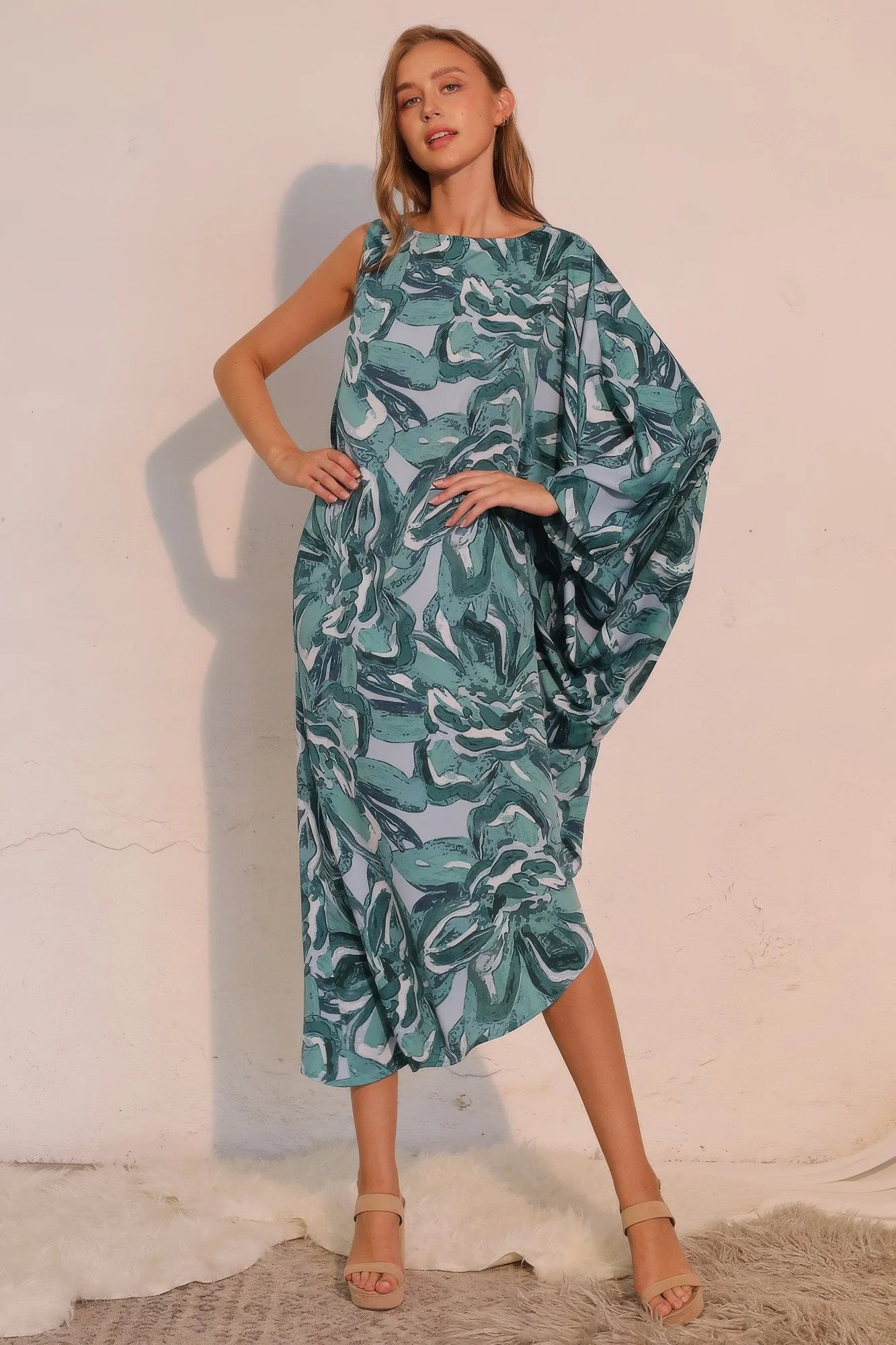 Woman wearing a green leaf-patterned dress against a white background