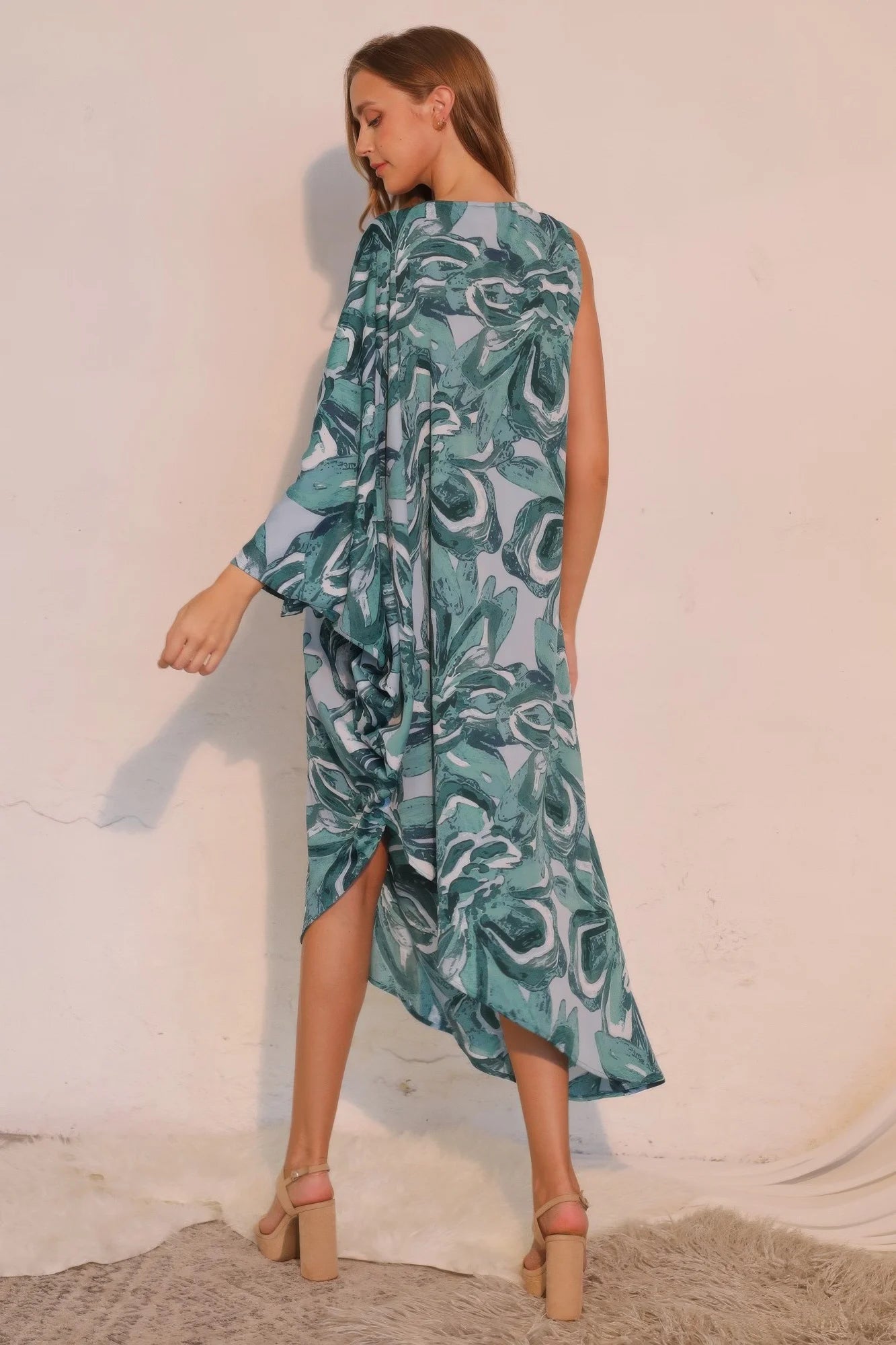 Woman wearing a blue and green patterned dress against a white background