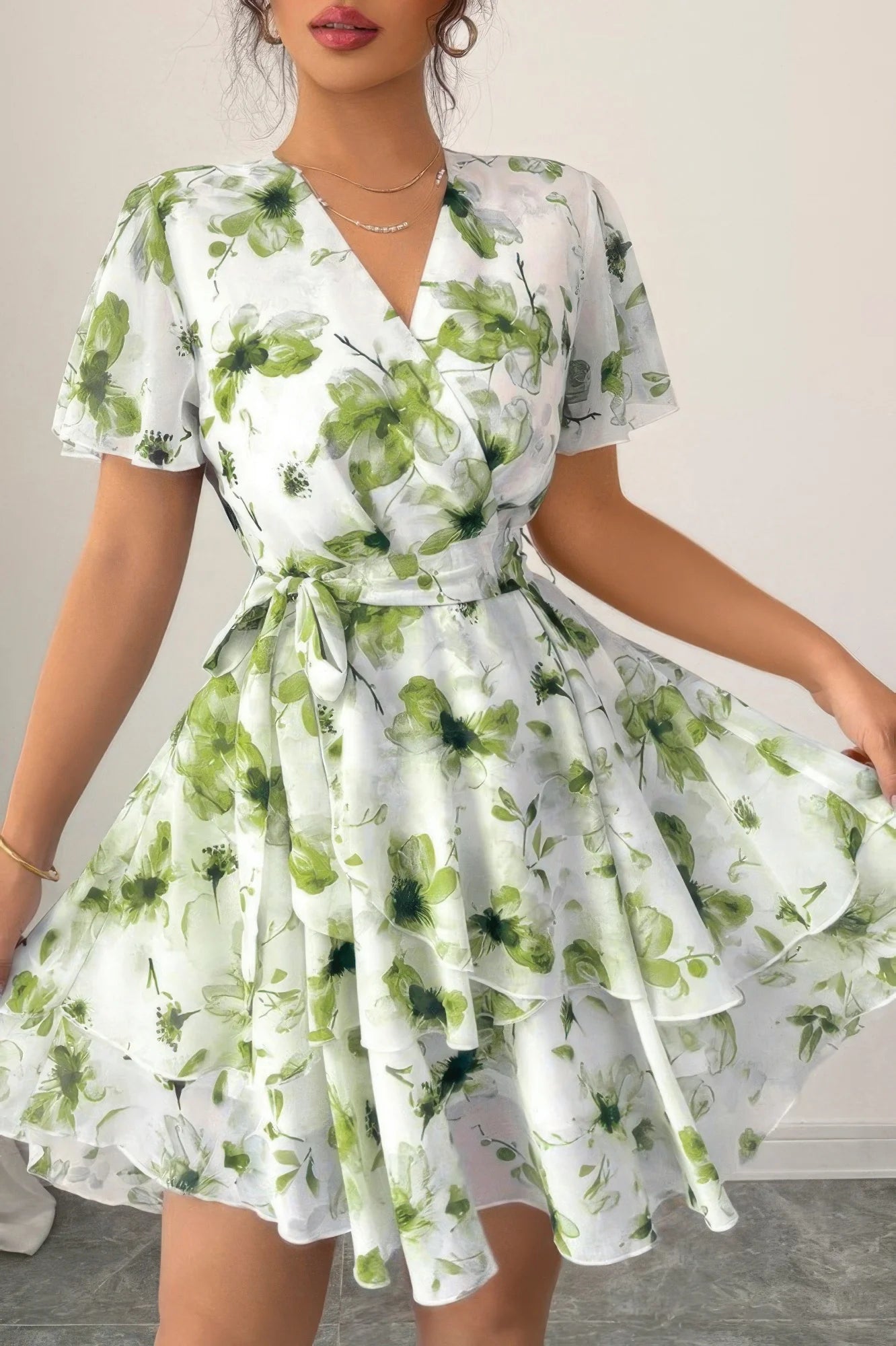 Woman wearing a white dress with green floral pattern on a plain background
