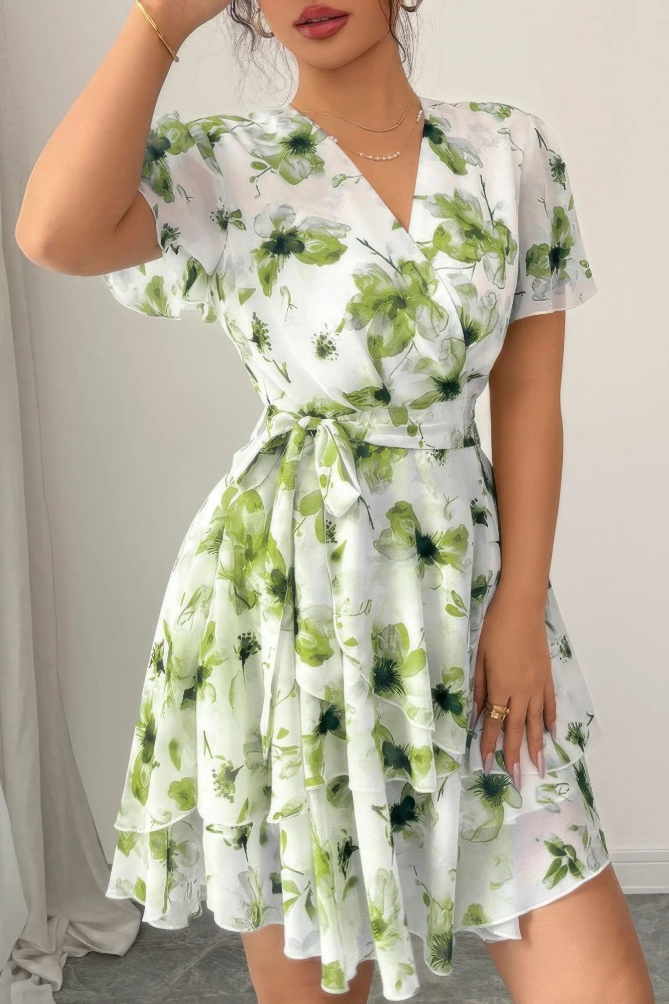 Woman wearing a floral dress with green and white pattern against a neutral background