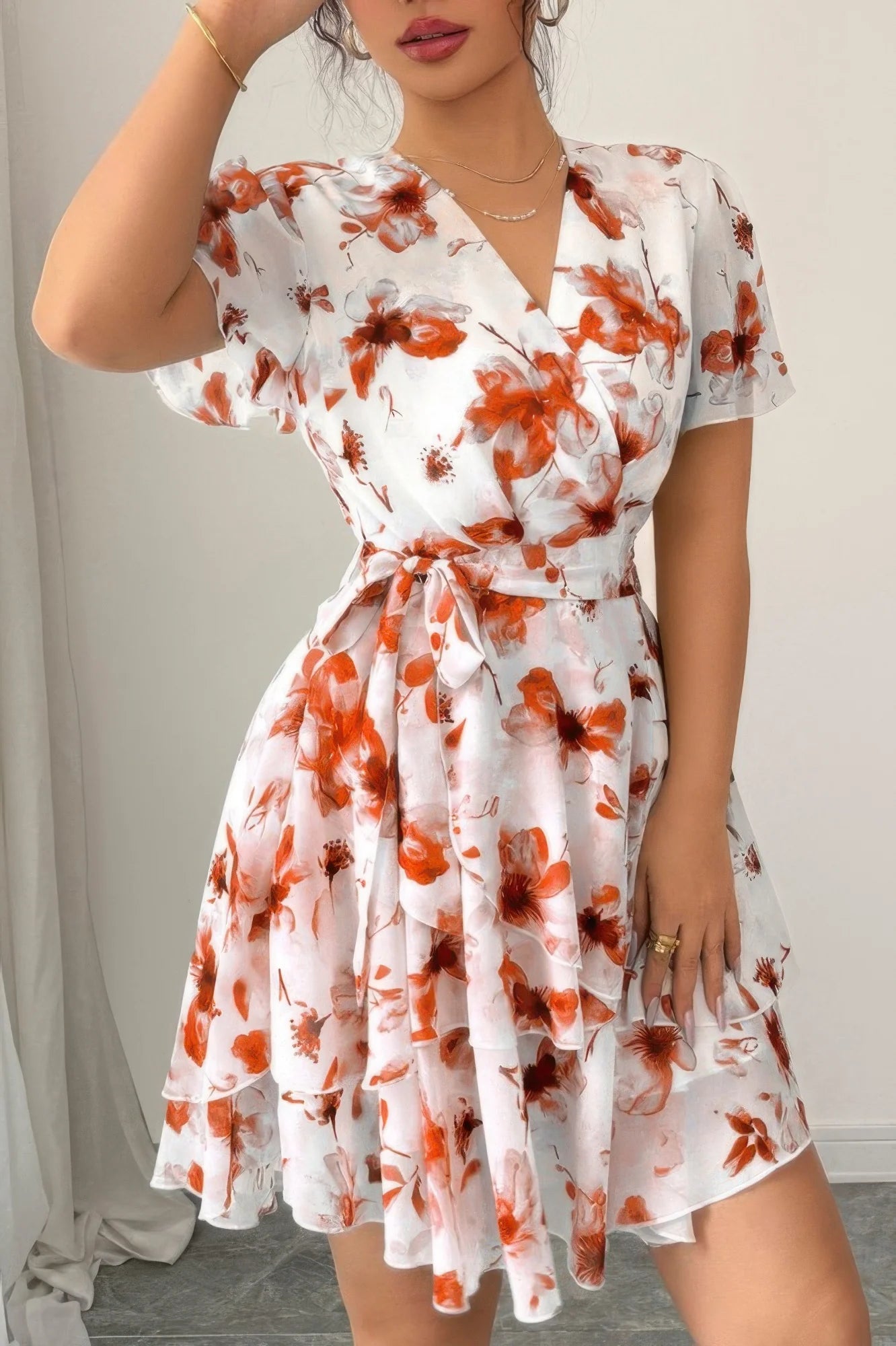 Woman wearing a white dress with orange floral pattern indoors.