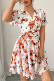 Woman wearing a white dress with orange floral pattern indoors.