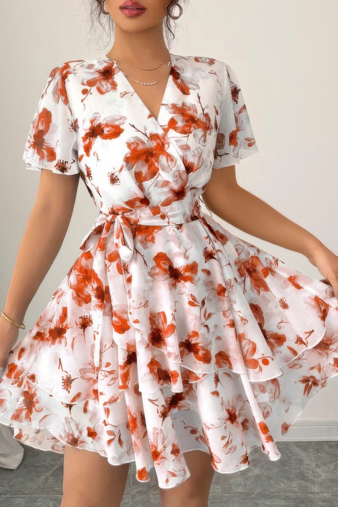 Woman wearing a white dress with orange floral pattern on a plain background