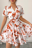Woman wearing a white dress with orange floral pattern on a plain background