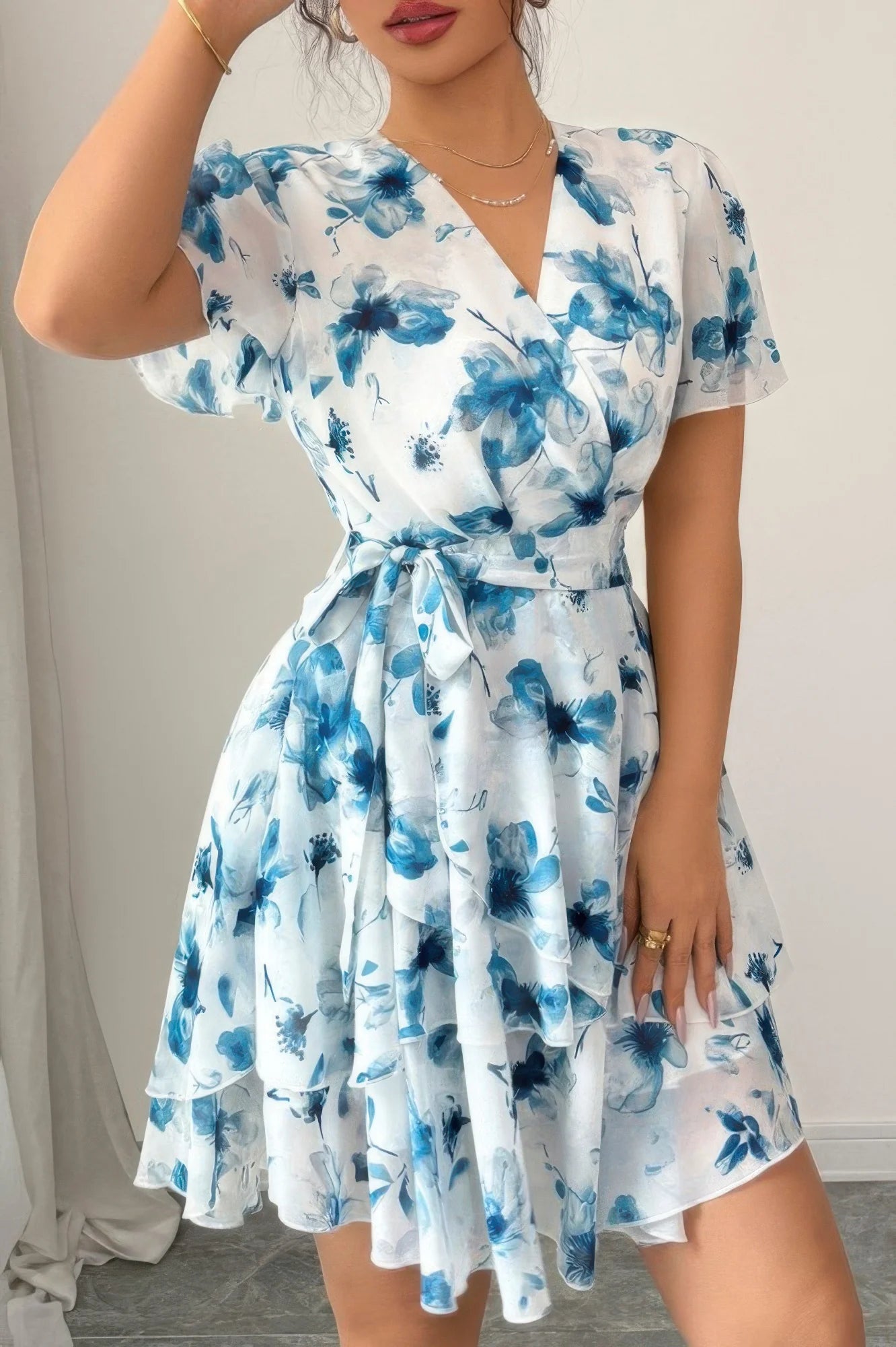 Woman wearing a blue and white floral dress against a neutral background
