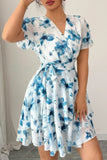 Woman wearing a blue and white floral dress against a neutral background