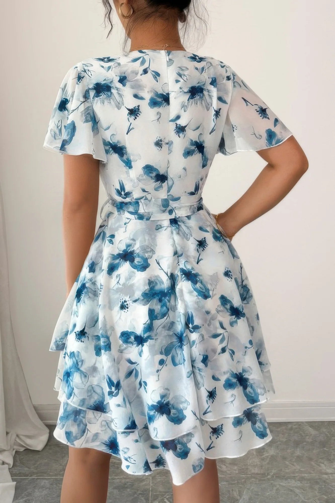 Woman wearing a blue floral dress against a plain background