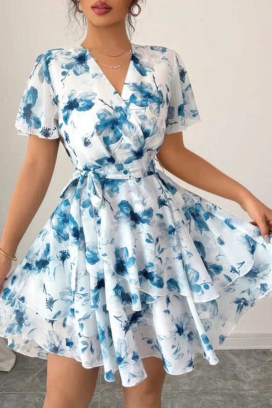 Woman wearing a white dress with blue floral pattern on a plain background