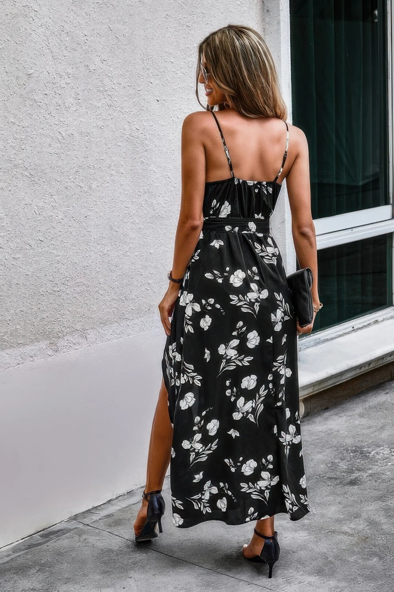 Woman wearing a black floral dress with a white wall and window in the background