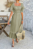 Woman in a green dress holding a woven bag in an outdoor setting.