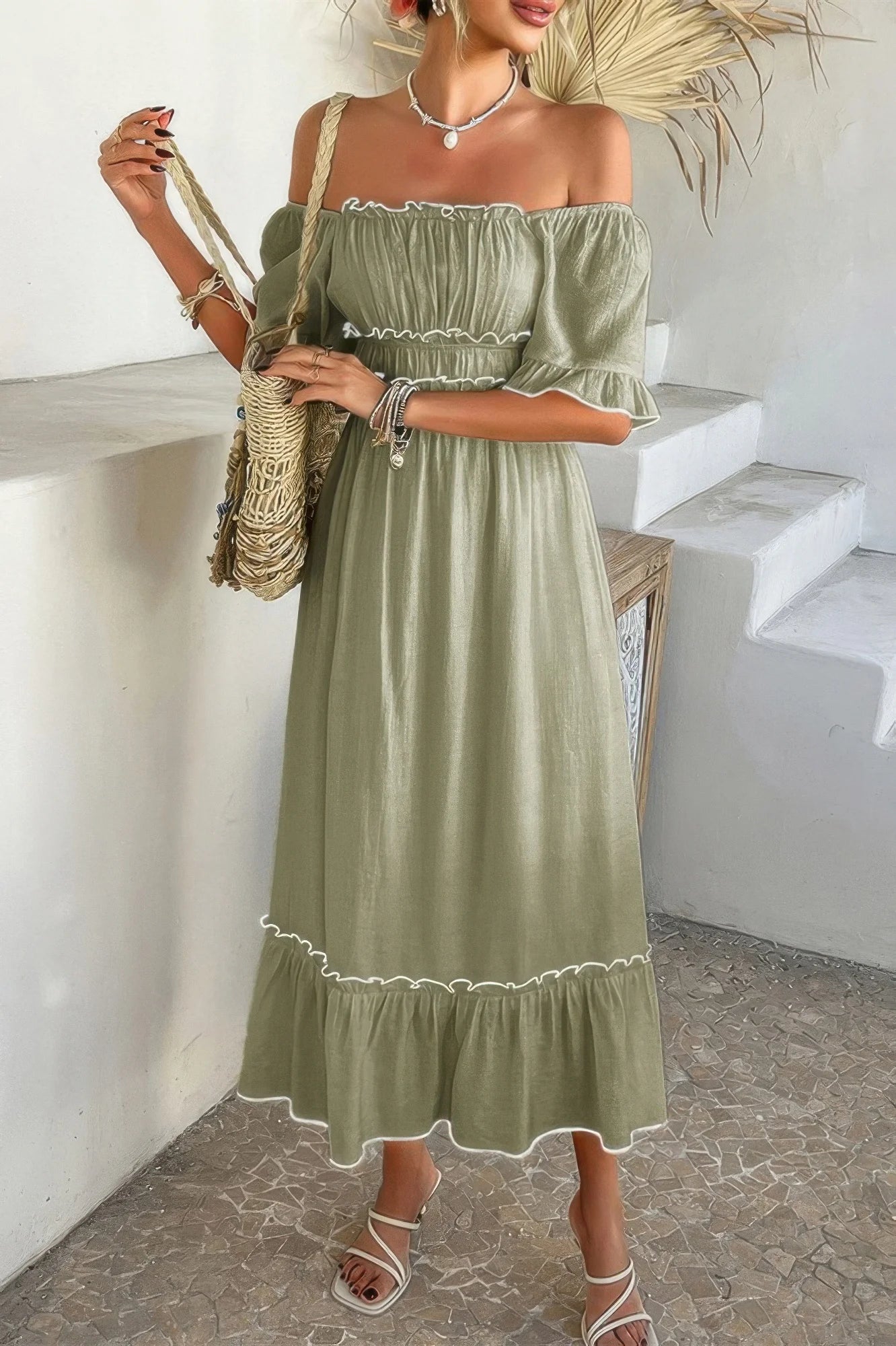 Woman wearing a green off-shoulder dress with white trim in an outdoor setting.