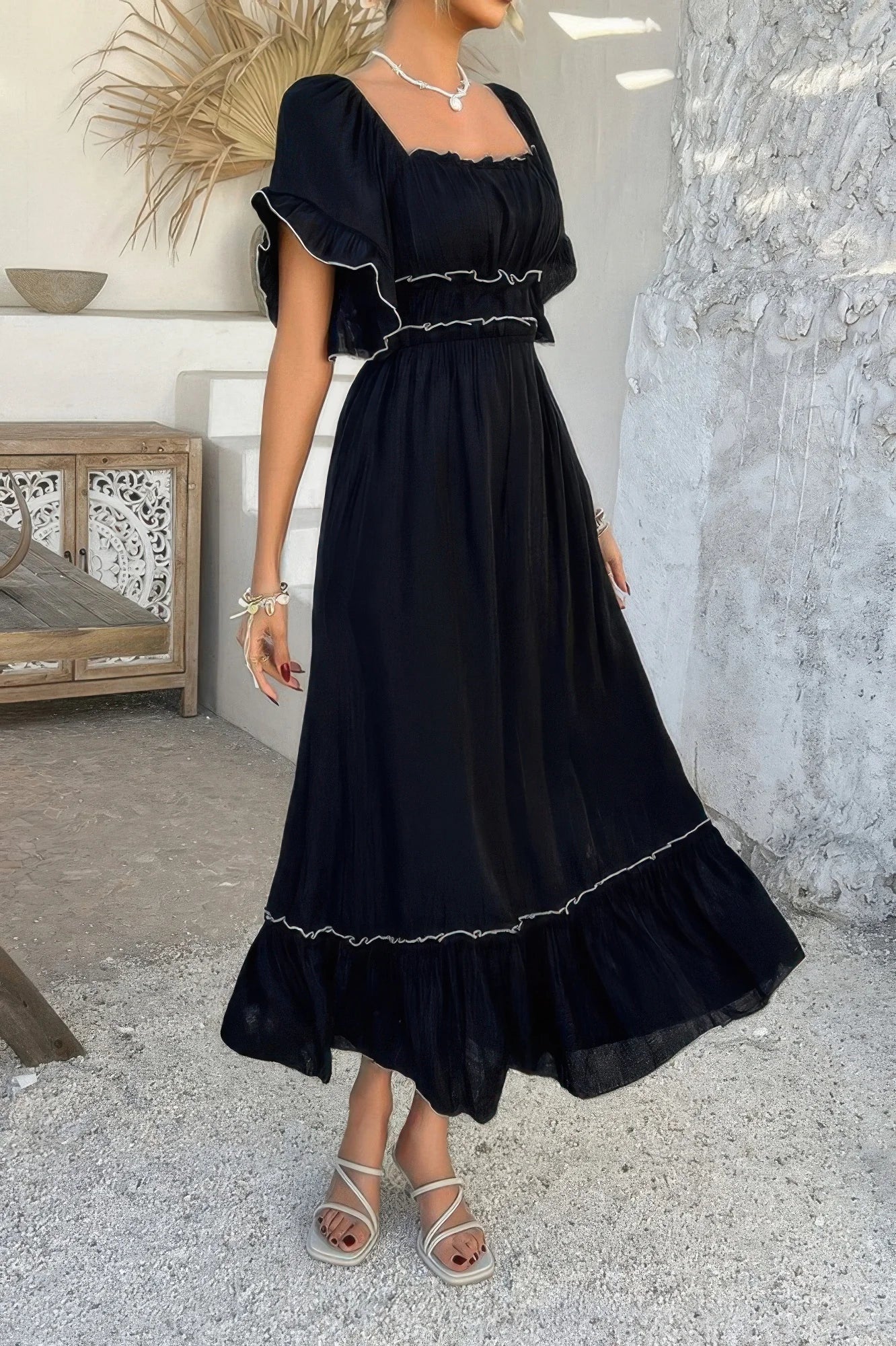 Woman wearing a black dress with white trim in an indoor setting.