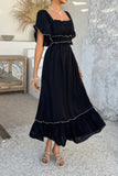Woman wearing a black dress with white trim in an indoor setting.