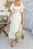 Woman in a white dress holding a straw bag in an outdoor setting