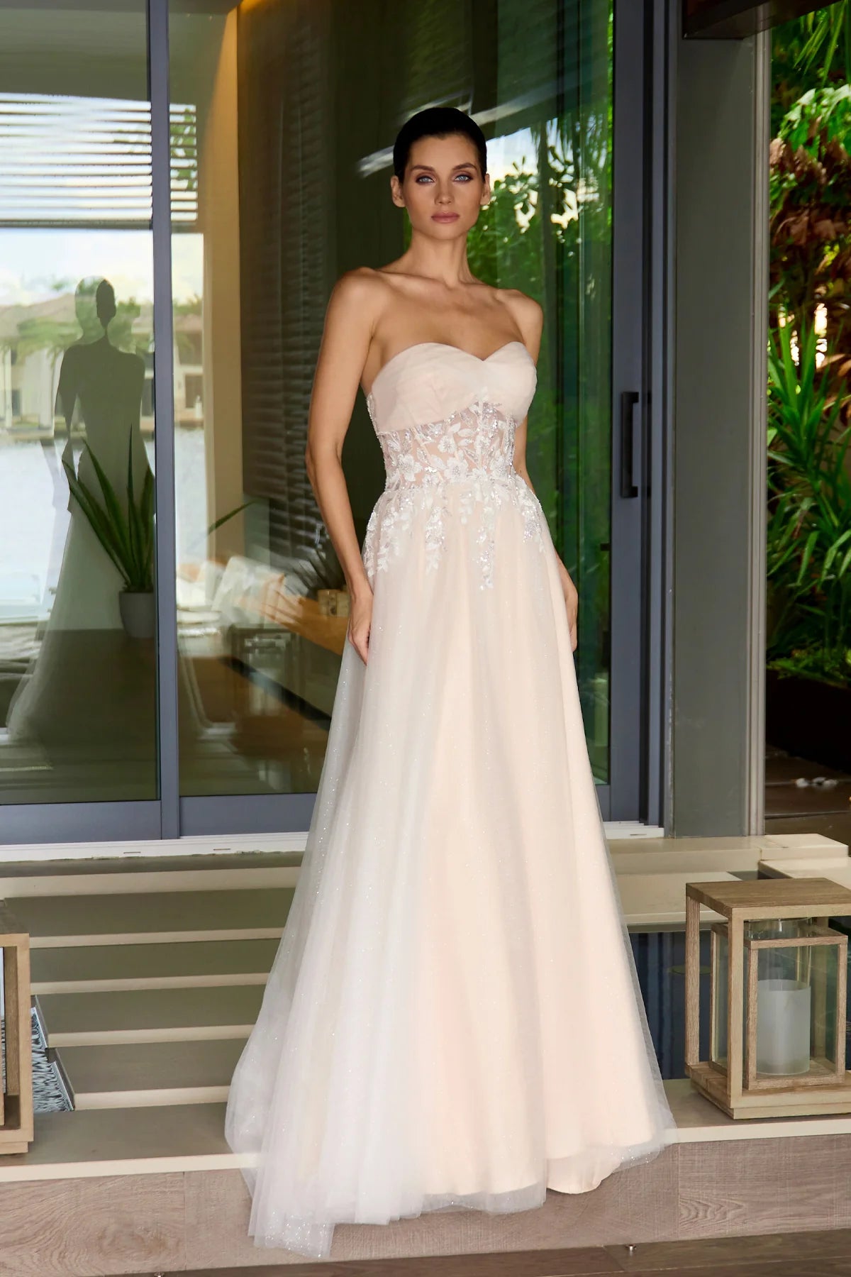 Woman in a strapless nude wedding gown standing on a porch.
