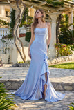 A woman stands outdoors on stone pavement wearing the Juliet JT2727H Long Prom Dress in periwinkle, featuring spaghetti straps, a fitted bodice, and ruffle detailing on the floor-length skirt.