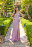 Wearing the Juliet JT2730H long lilac prom dress with sparkly sequins and a thigh-high slit, a woman stands on a garden stone path.