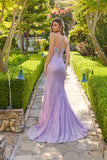 Wearing the Juliet JT2730H long prom dress, a woman stands on a stone path in a garden, her shimmering lavender gown sparkling as she faces away from the camera.