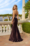 A woman in the Juliet JT2736S long prom dress with a beaded corset bodice stands on a stone terrace with white balustrades and greenery, her back to the camera.