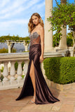 A woman stands outdoors in the Long Prom Dress: Juliet JT2736S in brown, featuring a strapless beaded corset bodice, draped satin skirt, and thigh-high slit, set against elegant columns and lush greenery.