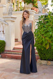 A woman wearing the Long Prom Dress: Juliet JT2736S with a beaded corset bodice and high slit smiles outdoors by a staircase and greenery.