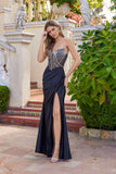 A woman poses outdoors near greenery and stone steps wearing the Juliet JT2736S long black prom dress, featuring a strapless design, sheer structured bodice, and high slit.