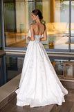 Woman in a white wedding dress with an open back standing in front of a modern interior.