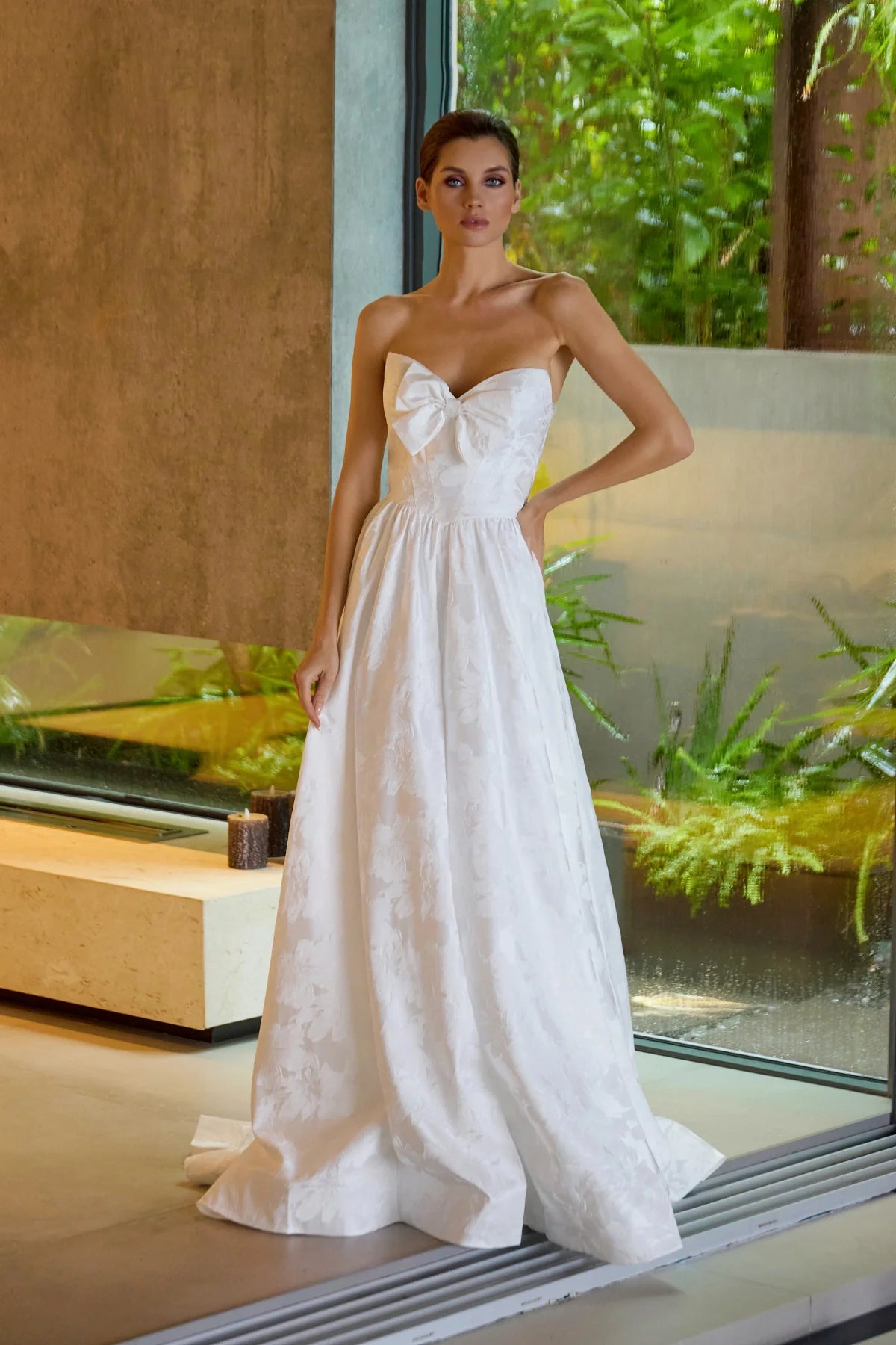 Woman wearing a white strapless dress with a bow detail in an indoor setting.