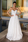 Woman in a strapless white wedding dress standing indoors.