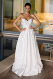 Woman in a strapless white wedding dress standing indoors.