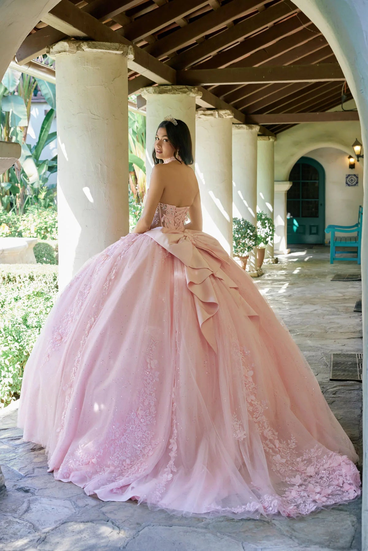Woman in a pink ball gown standing in front of a building with columns.
