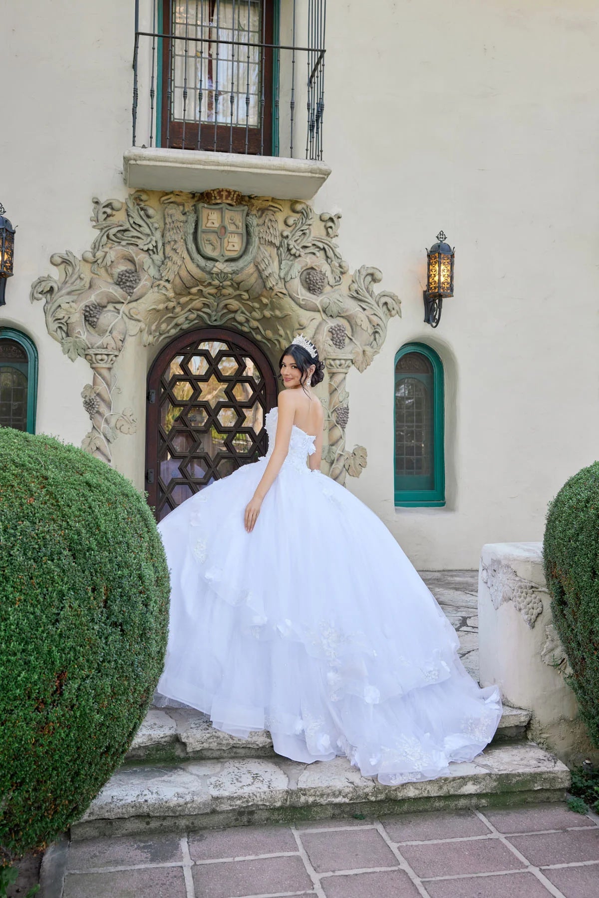 Woman in a white wedding dress standing in front of an ornate building entrance.
