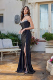 Wearing the Juliet JT2698A, a strapless satin prom dress with a corset bodice, hot stone embellishments, and a thigh-high slit, a woman stands on a patio near garden and outdoor furniture.