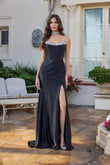 A woman poses outdoors in front of a white house, wearing the Juliet JT2698A long black prom dress with a strapless satin corset bodice, hot stone embellishments, high slit, and a matching choker necklace.
