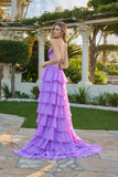 A woman stands outdoors in the Juliet JT2738S Long Prom Dress, featuring a strapless corset bodice and chiffon ruffle skirt, looking over her shoulder amid greenery and white columns.
