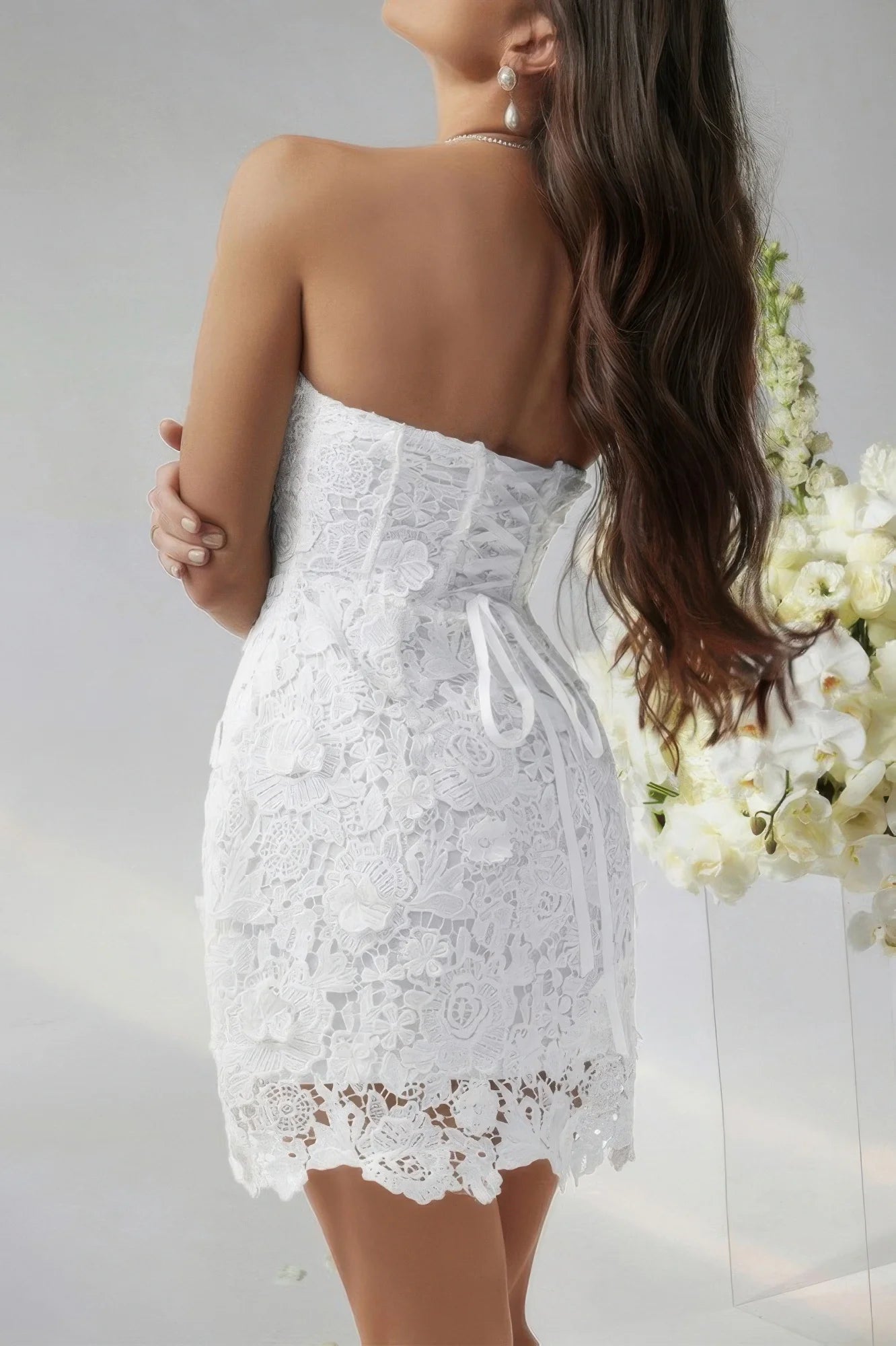 White lace strapless dress worn by a person with a neutral background