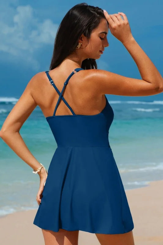 Woman in a blue swim dress standing on a beach with ocean view