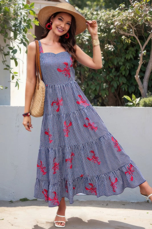 Woman wearing a blue dress with red patterns and a straw hat, standing outdoors.