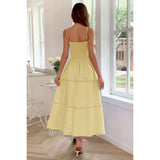 Woman wearing a yellow dress standing in a room with large windows.