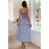 Woman wearing a light blue dress standing in a room with large windows.