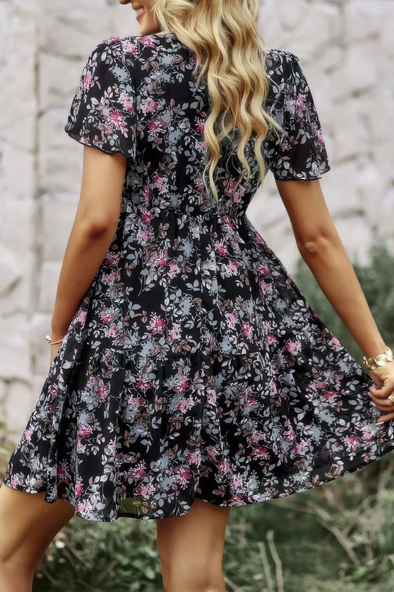 Woman wearing a black floral dress with a blurred natural background