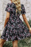 Woman wearing a black floral dress with a blurred natural background