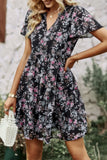 Woman wearing a black floral dress with a blurred outdoor background