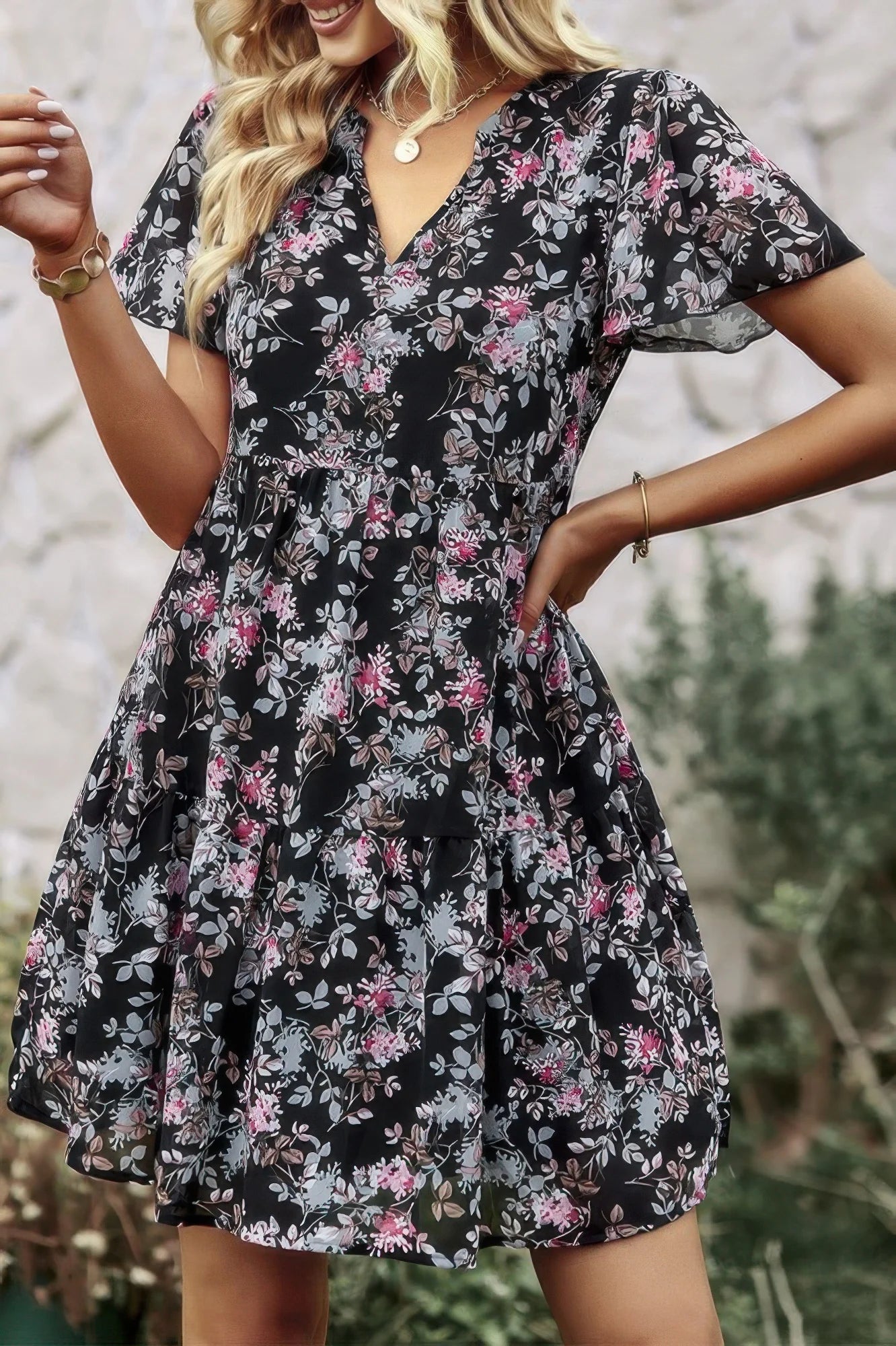 Woman wearing a black floral dress with a blurred natural background