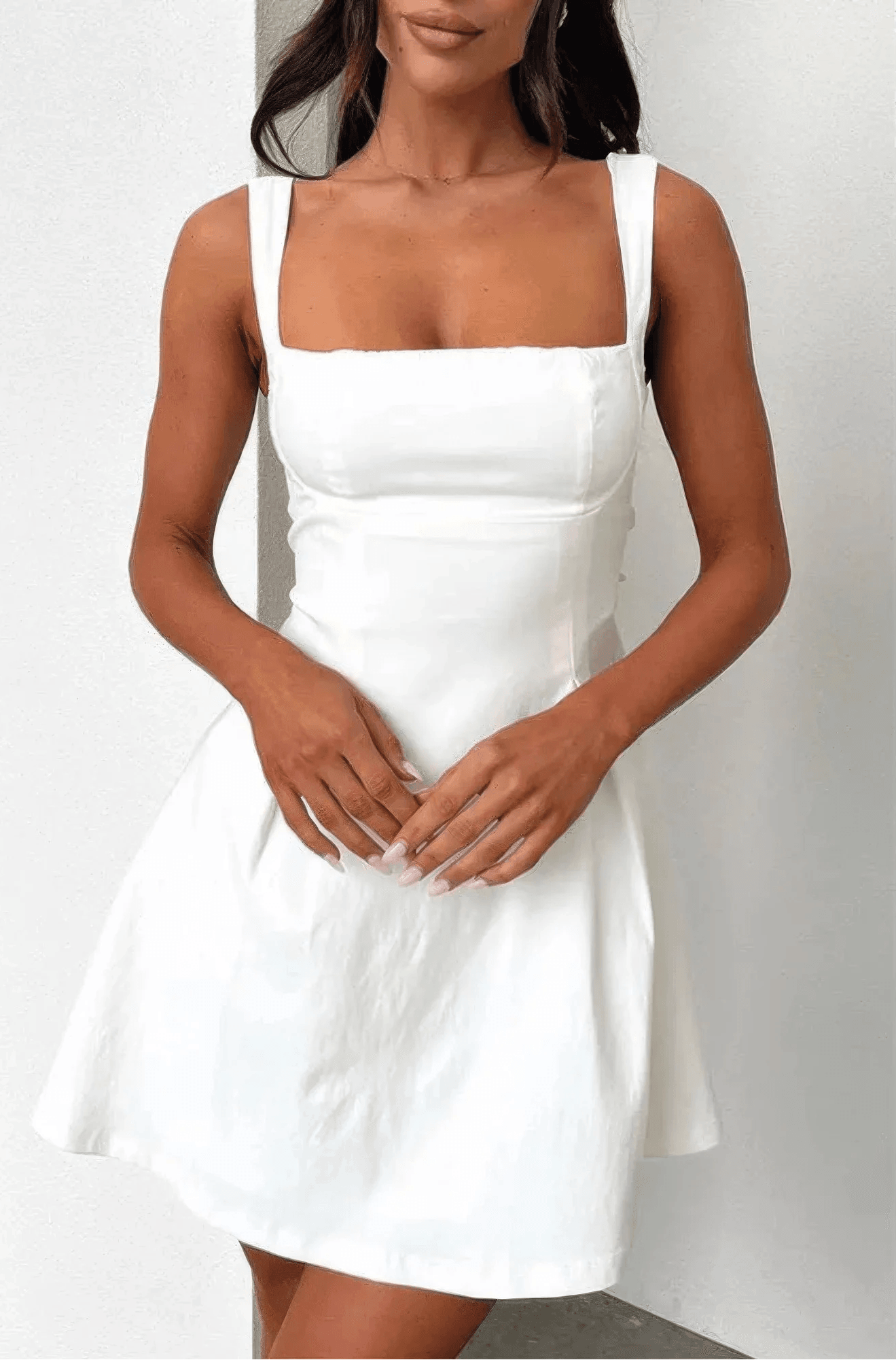 Woman wearing a white dress against a plain background
